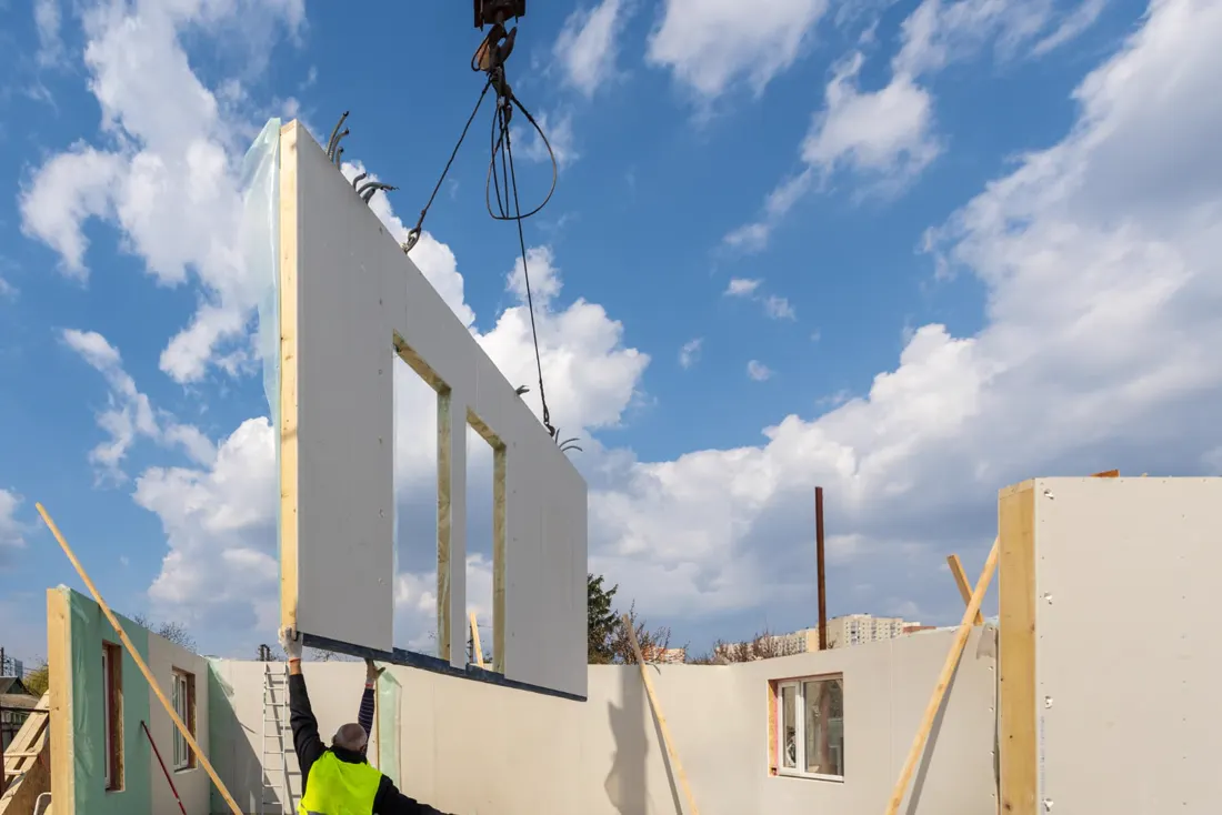 Een prefab HSB-gevelelement wordt met een kraan op zijn plek gehesen